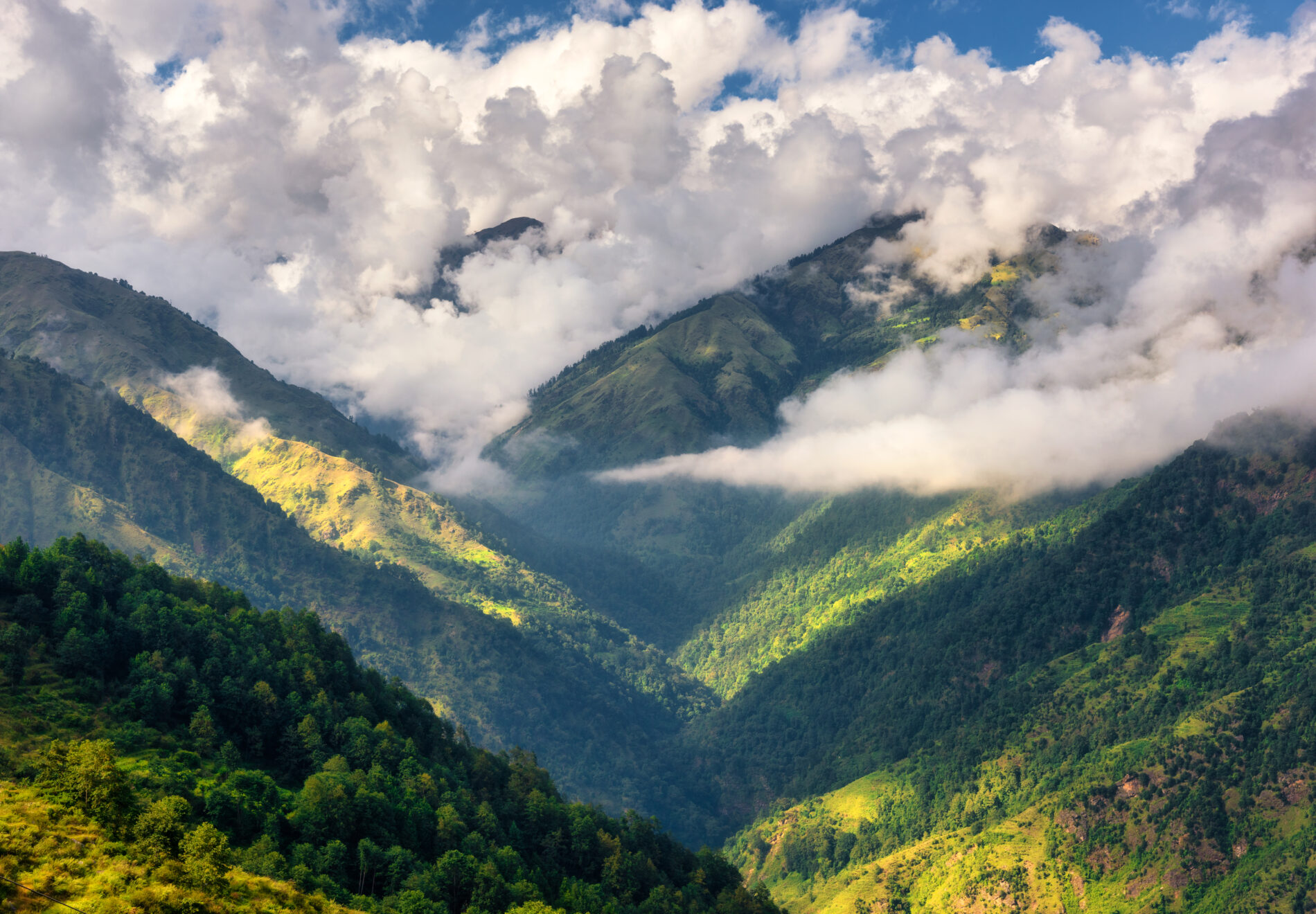 Mountains in low clouds at sunny day in summer. Nepal