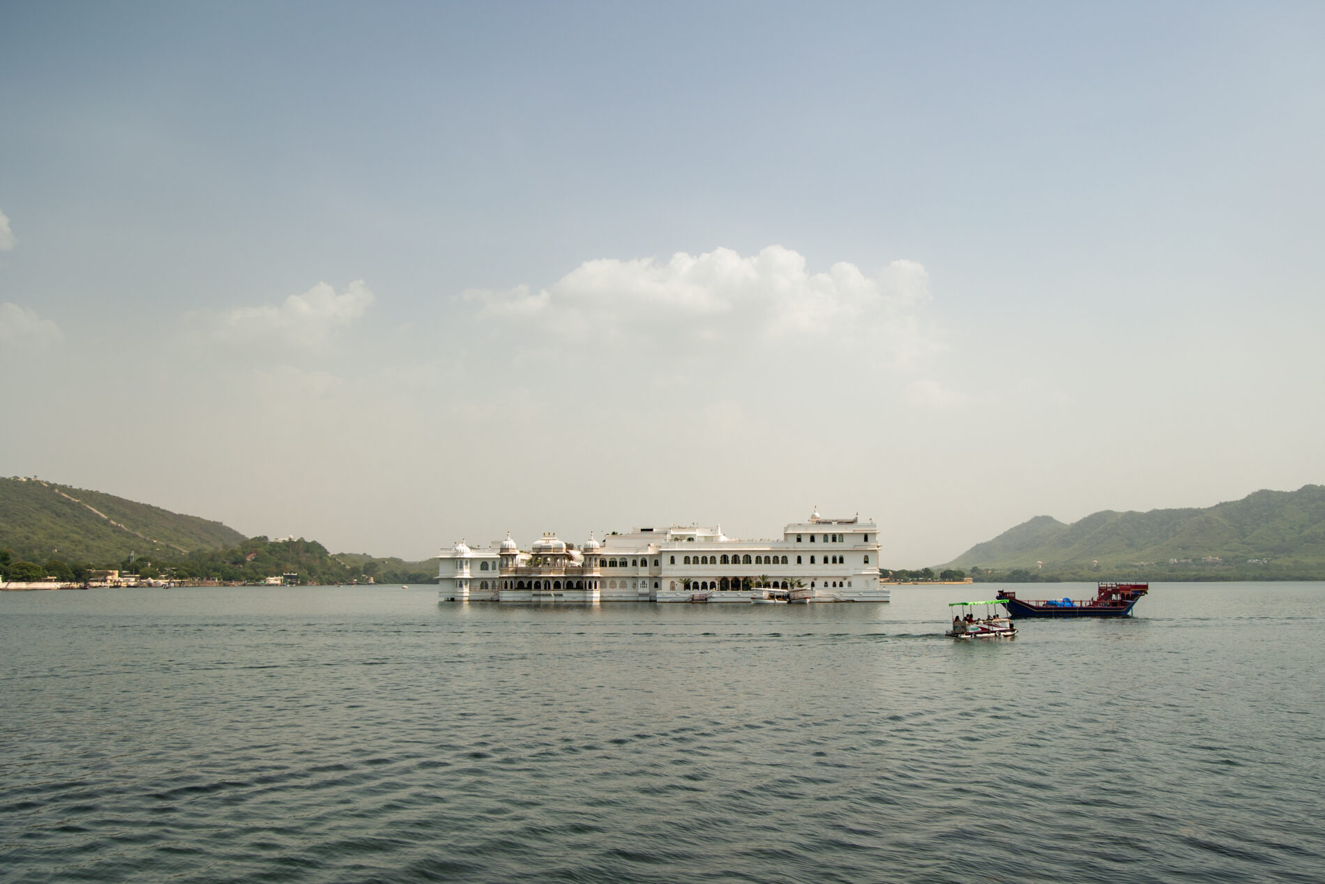 Lake Pichola reflecting Taj Lake Palace in Udaipur, India, with boats sailing
