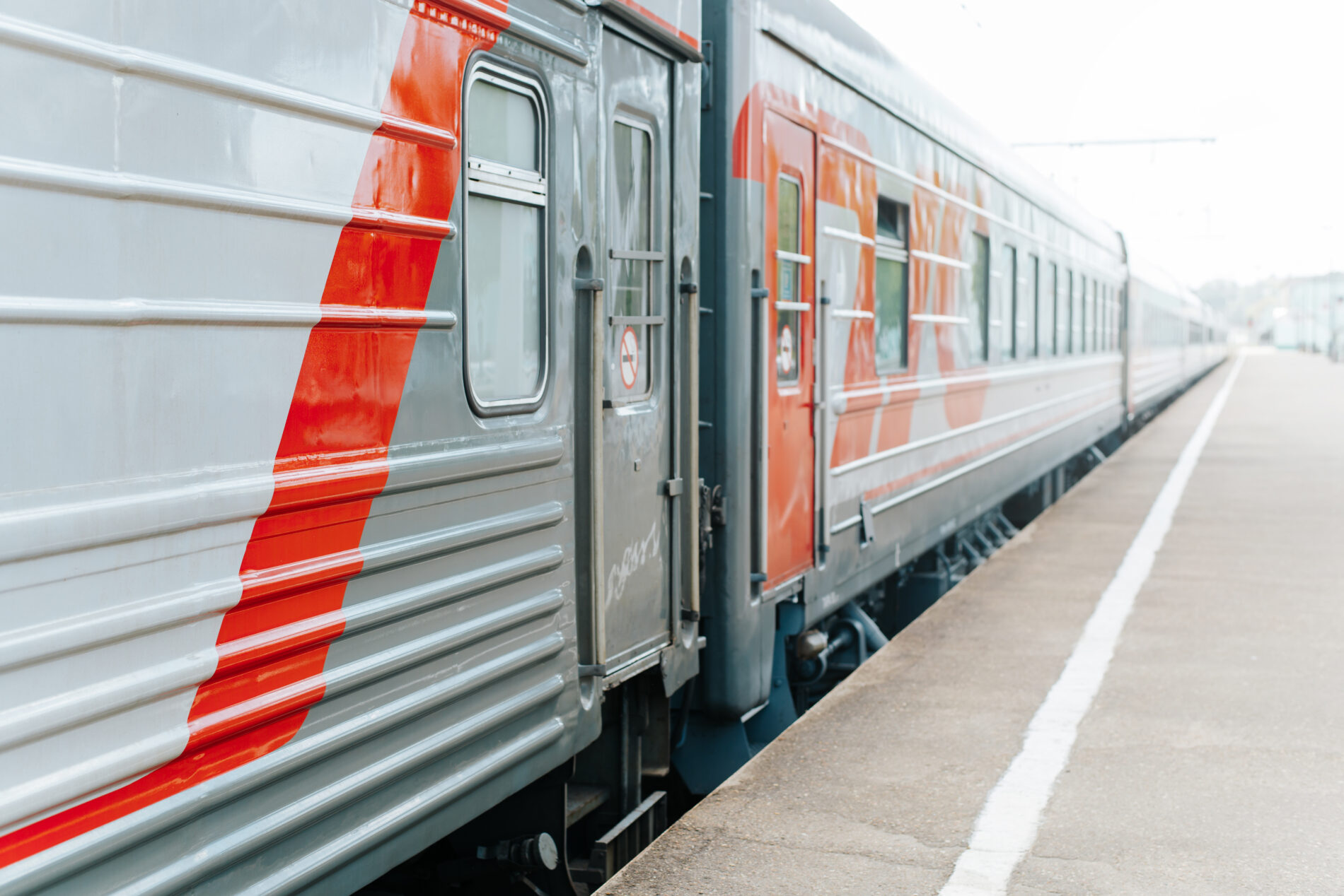 Modern high speed passenger train at railway station near an empty platform outdoors, side view. Perspective, selective focus, copy space
